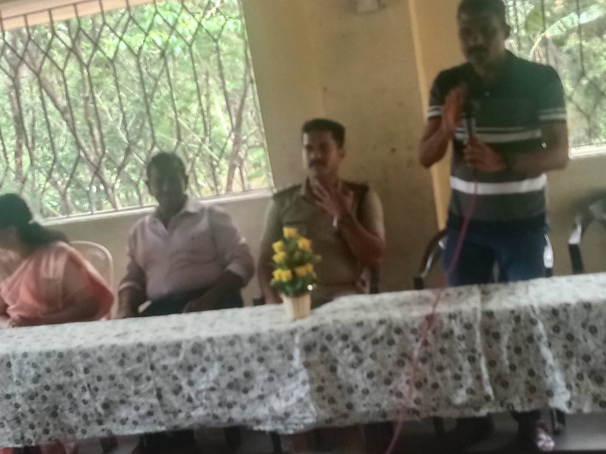 A speaker with a microphone standing at the table, a uniformed officer seated beside him.