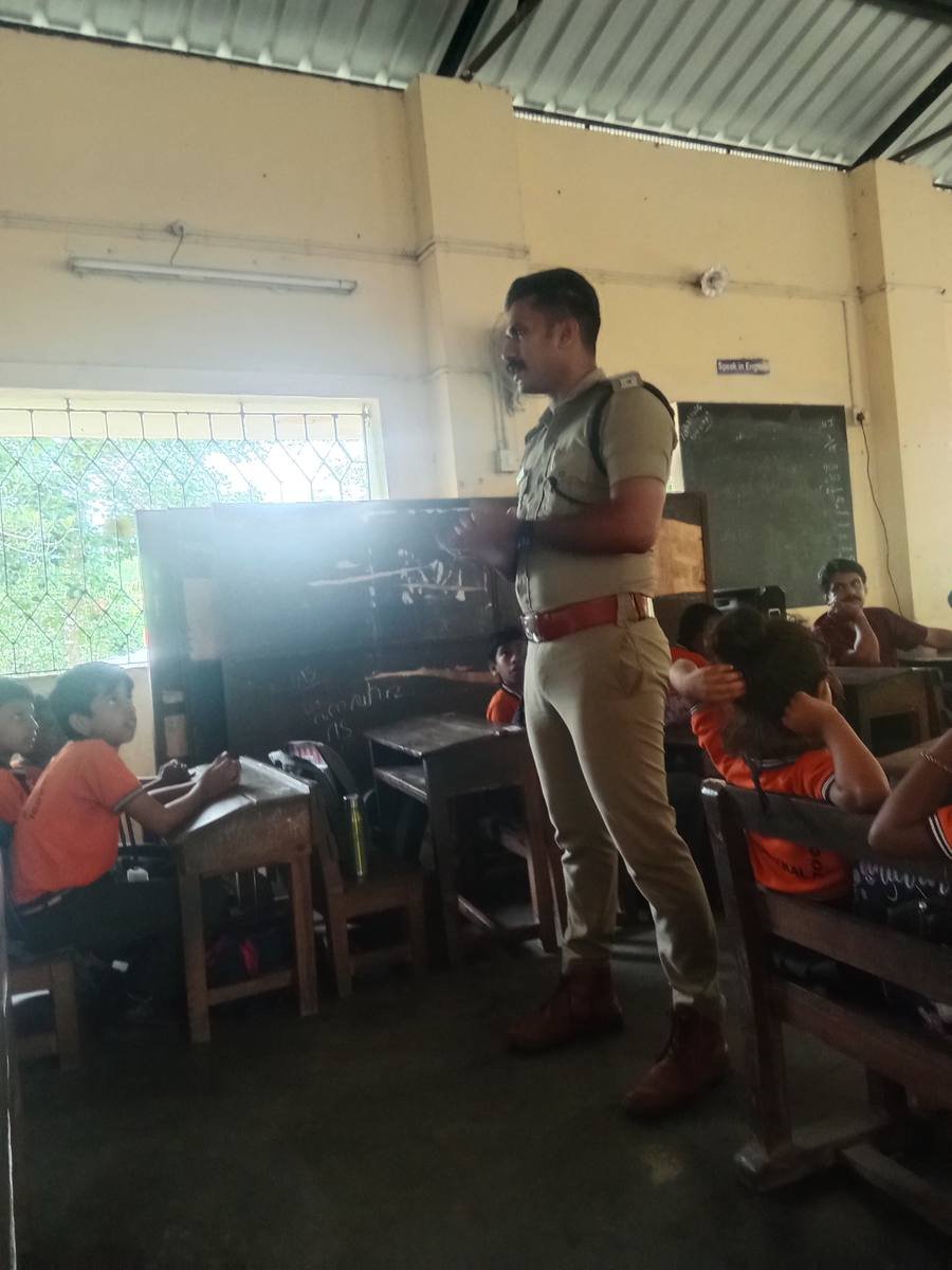 A uniformed officer speaking to the class from between the benches.
