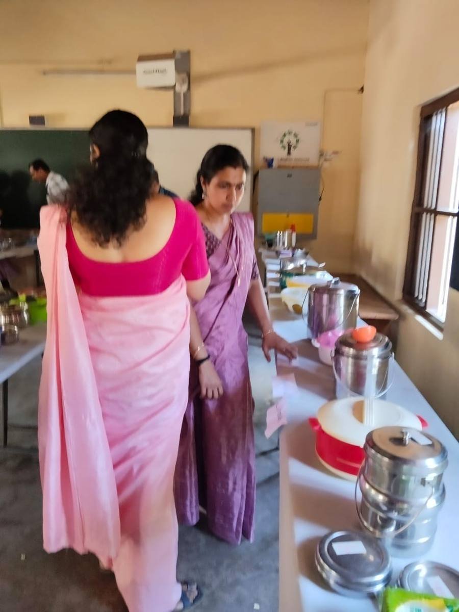 Two teachers walking the line of dishes, reading the labels as they go.