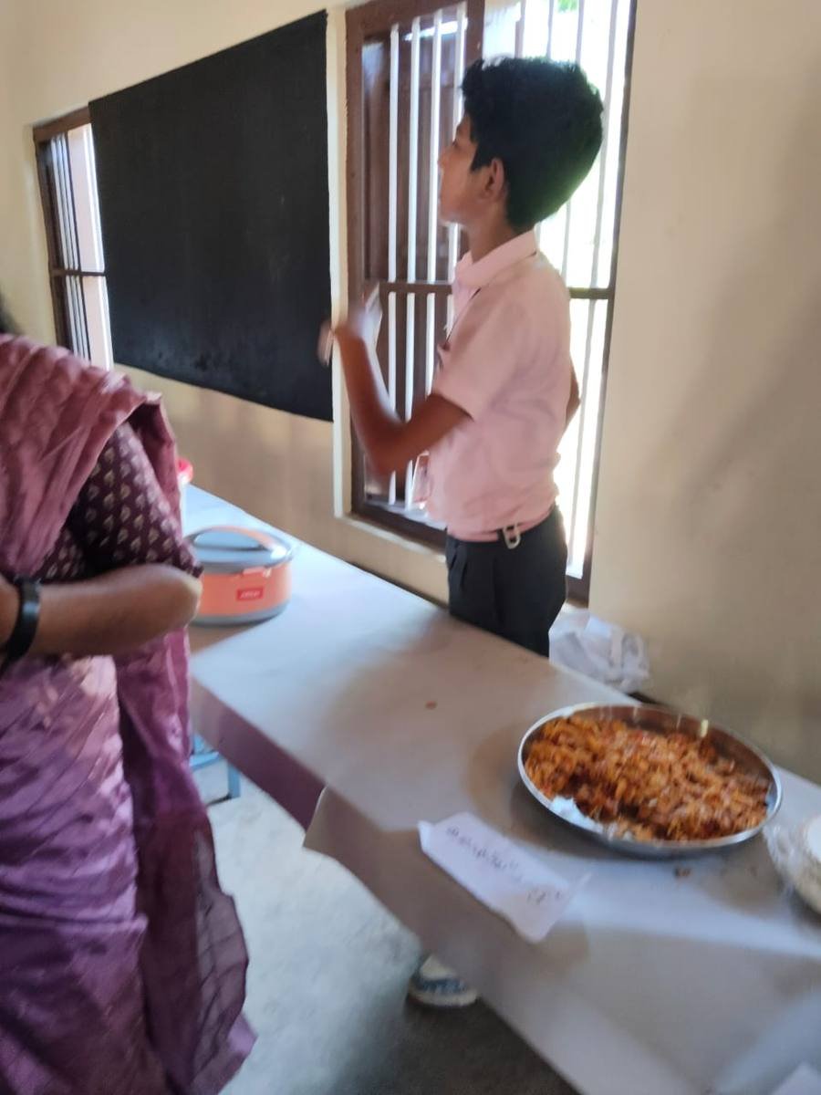 A pupil at the counter beside a large tray of fried snacks.