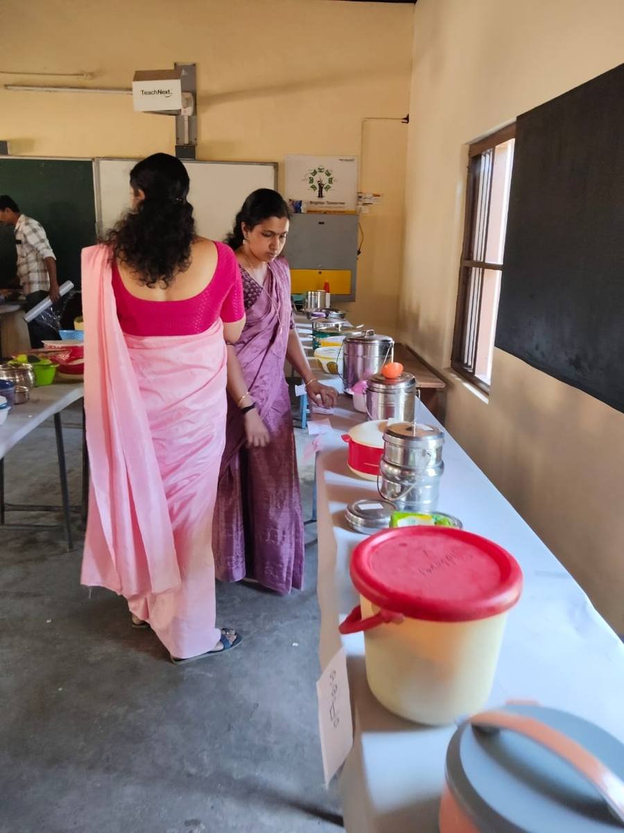 Teachers looking over the entries, the labelled dishes running the length of the table.