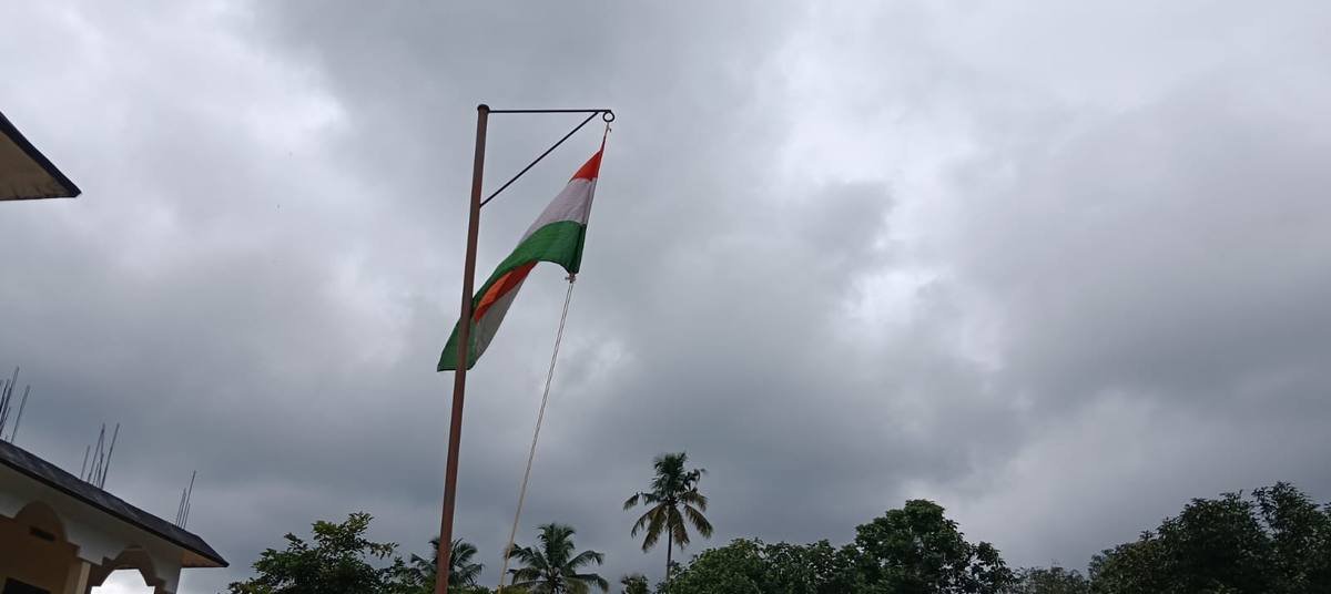 The national flag flying from the school flagstaff against a clouded monsoon sky.