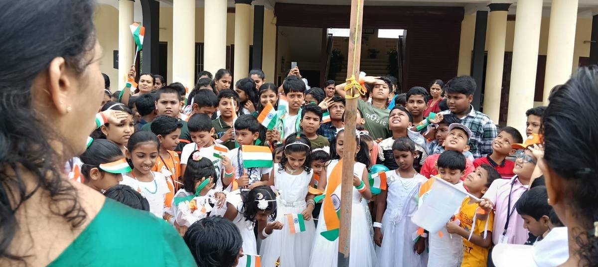 Pupils crowded round the flagstaff holding paper tricolours after the hoisting.