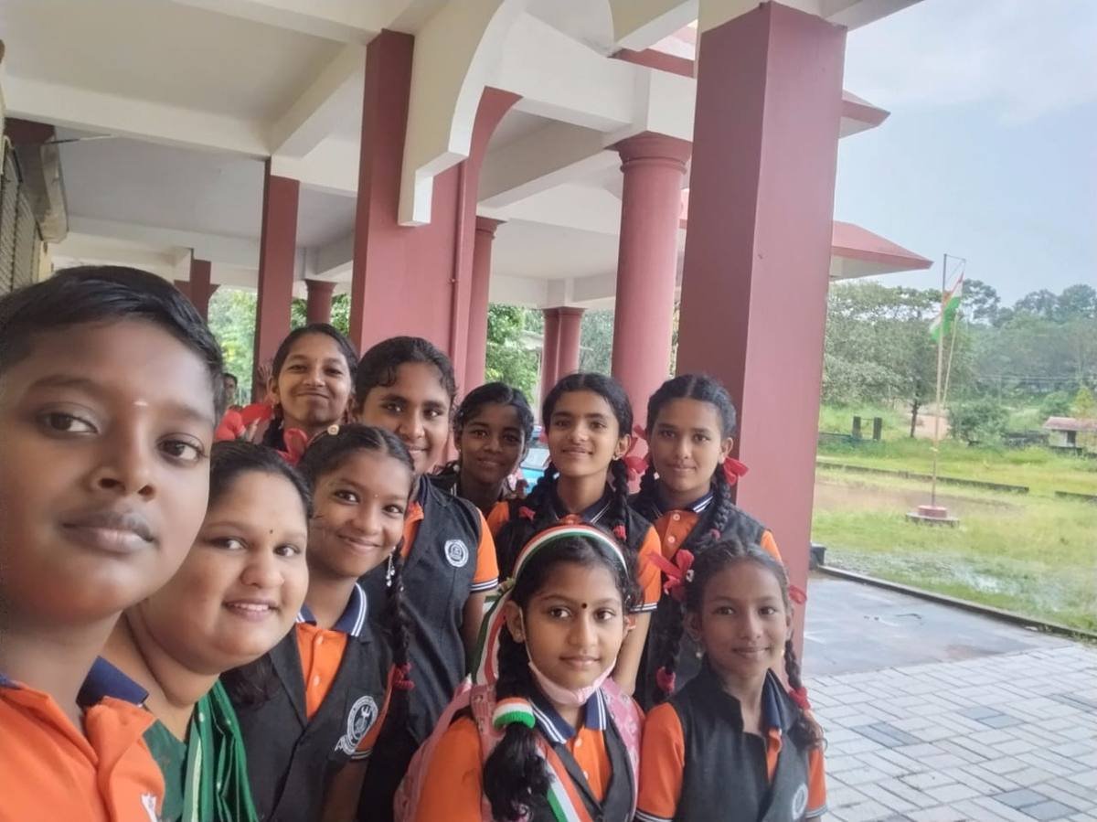 A group of girls in school uniform photographed in the veranda, the flag flying on the ground beyond.
