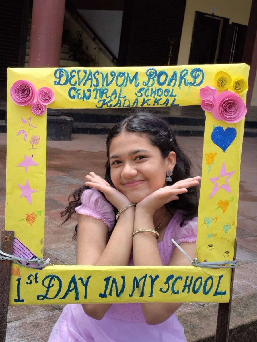 A pupil smiling behind the hand-made photo frame in the school veranda.