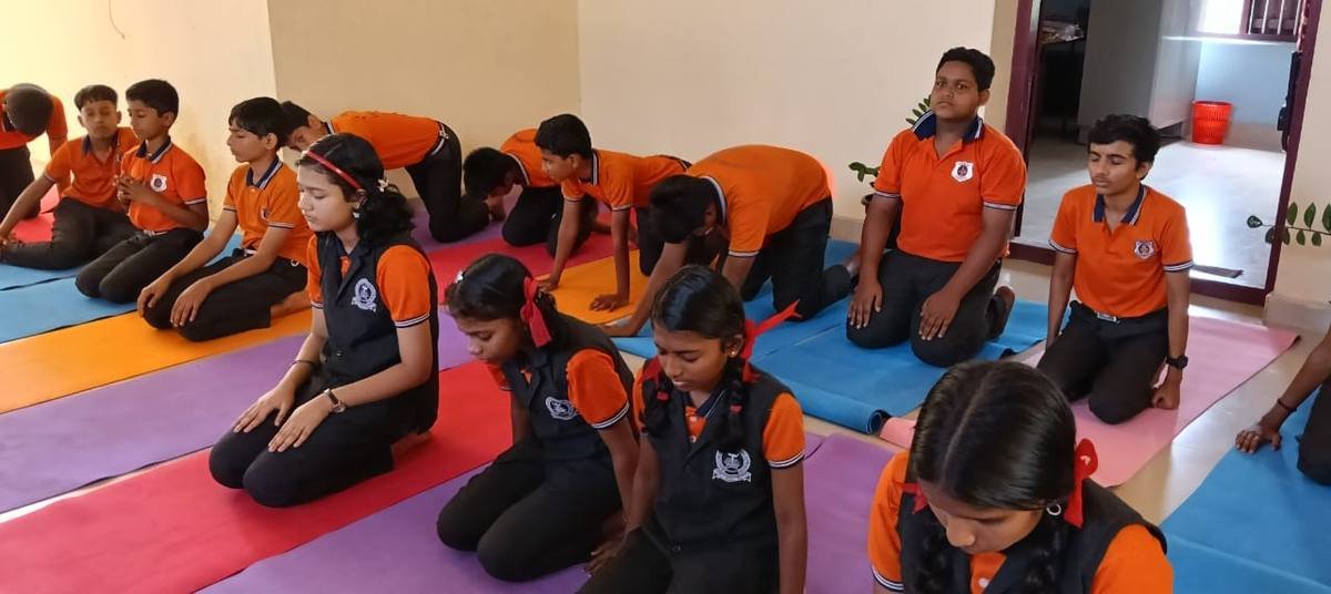 Senior pupils kneeling on their mats with eyes closed and hands resting on their knees.