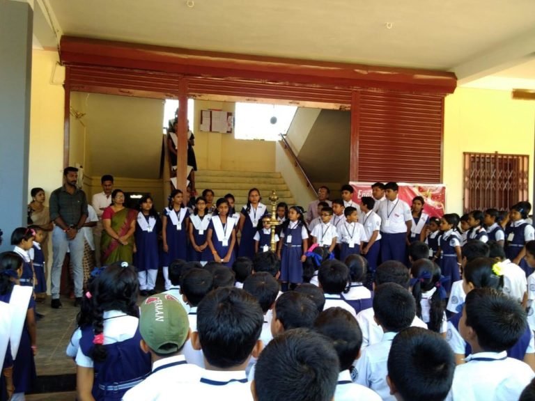 Students and staff gathered around the brass lamp in the school hall.