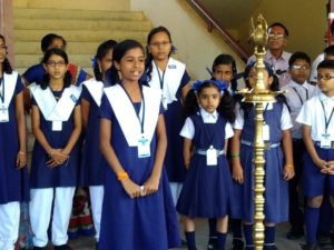 Students at assembly beside the lit brass lamp.